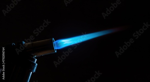A powerful butane torch lighter displaying a bright, hot blue jet flame against a dark background, showing intense heat output ,small ,focused ,equipment