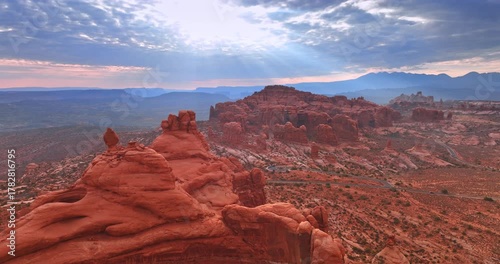 Orange rocks of whimsical shape in the deserted area. Beams of setting sun go through the cloudscape. Aerial perspective.