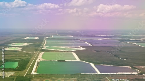 Airplane descending toward Miami with clear aerial view of large water basins and green land blocks below. Miami. USA.
