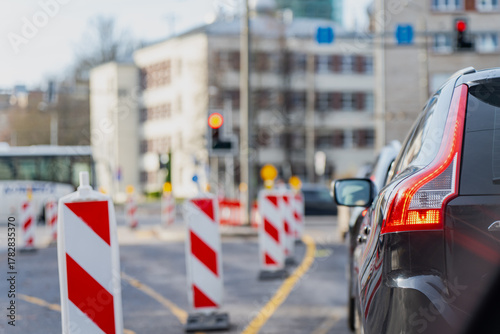 City street traffic slowed by construction barriers in Riga representing infrastructure maintenance, safety management and modern road organization during urban repair operations and control setup