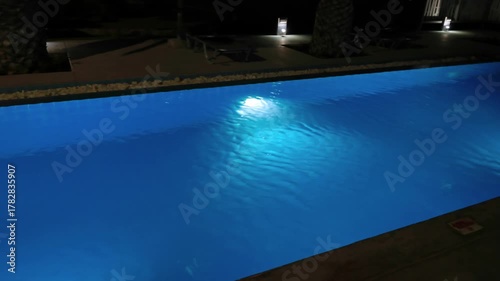 Night view of illuminated swimming pool with calm blue water and reflections on background. Kos. Greece.