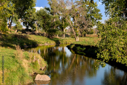 Quadro su tela Winding creek and water reflection of trees in green pasture farmland of southwe