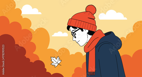 Young man in winter clothes watches a falling maple leaf in an autumn park, enjoying the serene beauty of nature on a crisp afternoon.