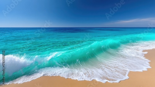 Fototapeta Naklejka Na Ścianę i Meble -  Vibrant turquoise ocean wave cresting on a sunlit sandy beach under a clear blue sky with sparkling water and white foam