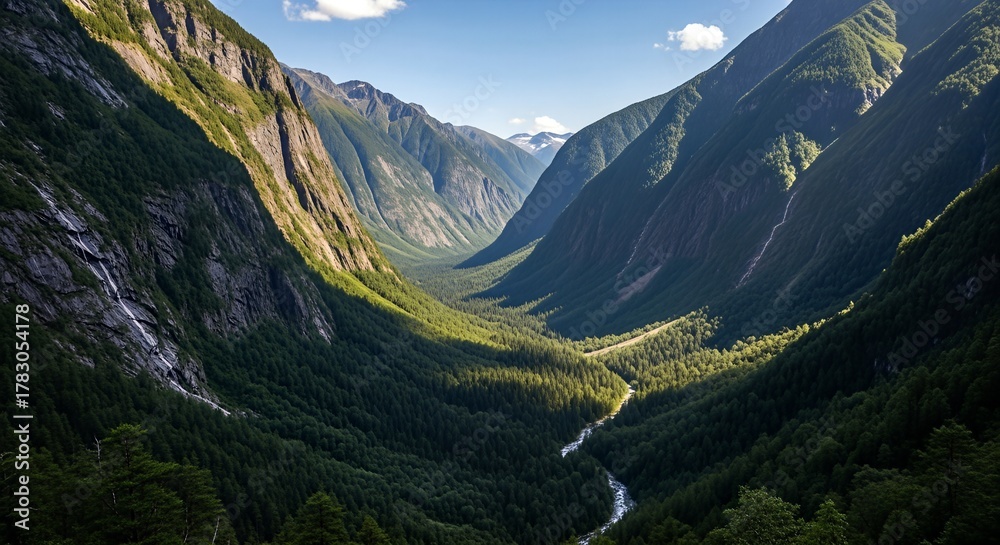Obraz premium Aerial view of a lush green valley with a river winding through it, surrounded by towering mountains.