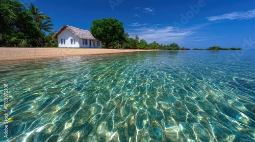 Tropical Beach Paradise White Hut With Thatched Roof Over Crystal Clear Turquoise Water Under Blue Sky And Lush Green Trees on a Sunny Day