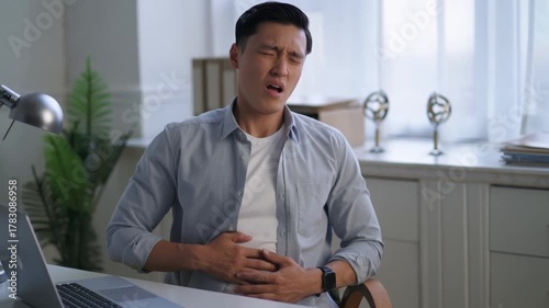 A man experiencing stomach pain while working at his desk Stock Video