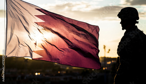 Patriotic soldier stands silhouetted with Qatar flag at sunset, representing national pride, military service, and unwavering dedication to country