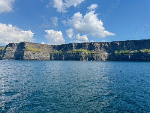 Coastal cliffs with deep blue sea under clear sky and clouds