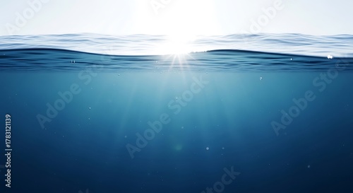 Fototapeta Naklejka Na Ścianę i Meble -  Sunlight pierces through the tranquil surface of the deep blue ocean water