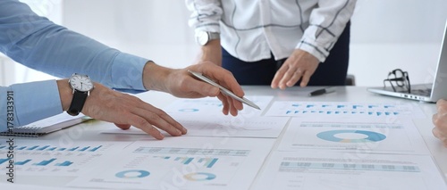 Business team discussing financial charts and strategy with graphs and data analysis documents on office desk during meeting for planning and corporate decisions