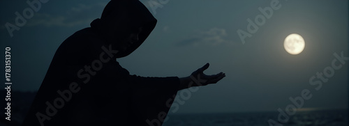 Silhouette of cloaked person reaching out under the full moon  