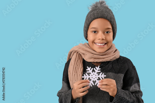 Little African-American boy in winter clothes with decorative snowflake on bl...