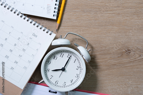 close up of calendar and alarm clock on the wooden table background, planning for business meeting or travel planning concept