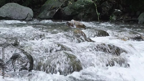 Clear water of the mountain river flows through the rocky contours of the river. The river water flows leisurely on the mountain rocks.