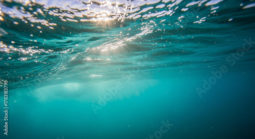 Underwater view of sunlight filtering through ocean waves, creating a serene atmosphere