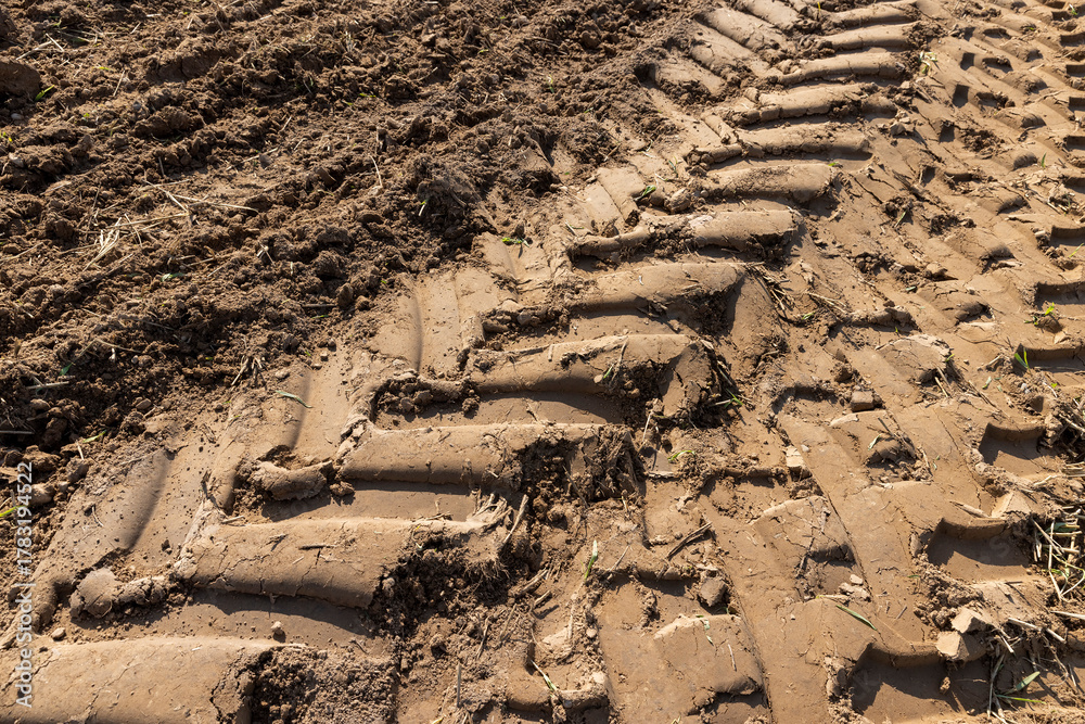 Fototapeta premium traces of a tractor on the soil during tillage, soil in a field with traces of passing heavy agricultural machinery after tillage