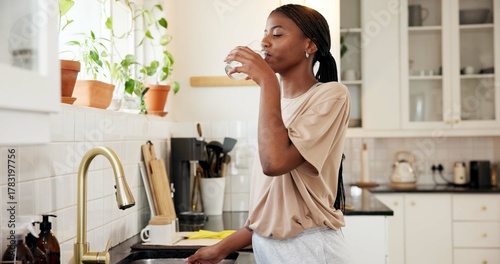 Home, thirsty and woman drinking water in kitchen for hydration, natural nutrients or detox. Apartment, black person and liquid beverage at faucet for refreshing drink, wellness and digestive health