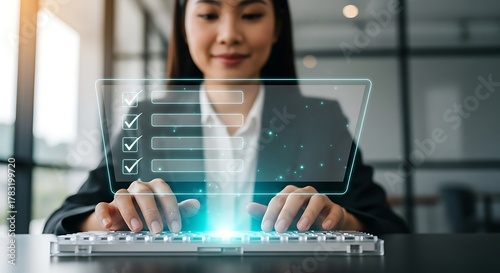 Asian businesswoman completing online form on computer with checklist.