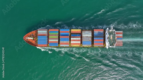 Aerial shot of cargo ship moving through ocean, global trade and logistics theme, blue-green water patterns, cinematic drone motion, 8K HDR detail. 