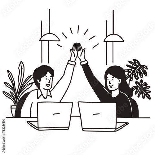 Successful business people giving each other a high five while working on laptop in coworking