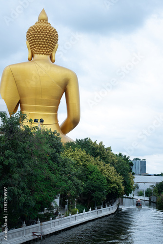 A big Buddha and small boat at canal line