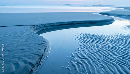 Serene beach landscape with a winding stream at dusk.
