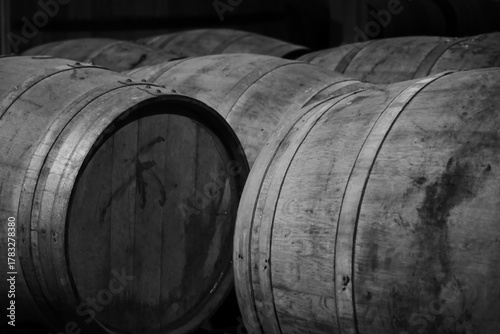 black and white image of dusty wooden barrels of rum in a large storage