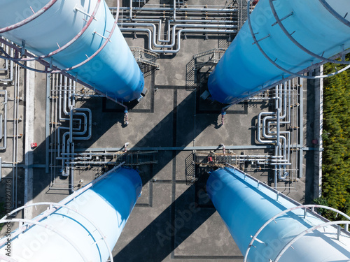 Industrial gas facility with blue towers, pipes, and power lines in rural area.