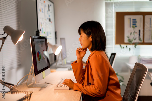 Woman analyzing data and working late in office