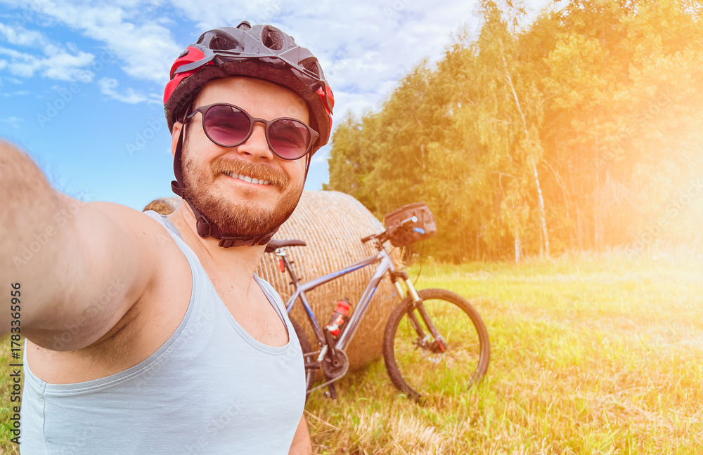 Fototapeta premium Cyclist taking selfie with mountain bike in field