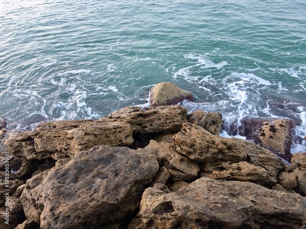 Naklejka premium Rocky Coastline with Ocean Waves Splashing against Natural Stone Shore