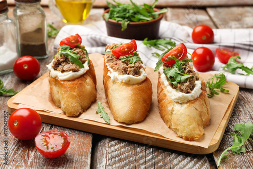 Foto Delicious bruschettas with tuna, cream cheese and tomatoes on wooden table, clos