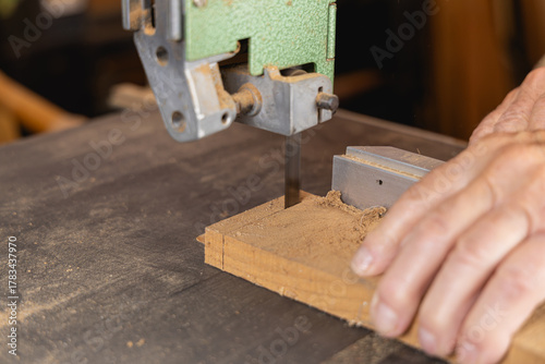 Plan serré sur les mains d’un menuisier guidant le bois sur la scie.