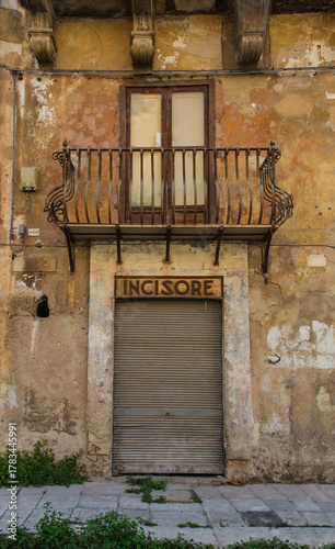 A door in an historic old building in Piazza Bologni in Palermo, Sicily, Italy. A former shop doorway. Above, a weathered sign reads 