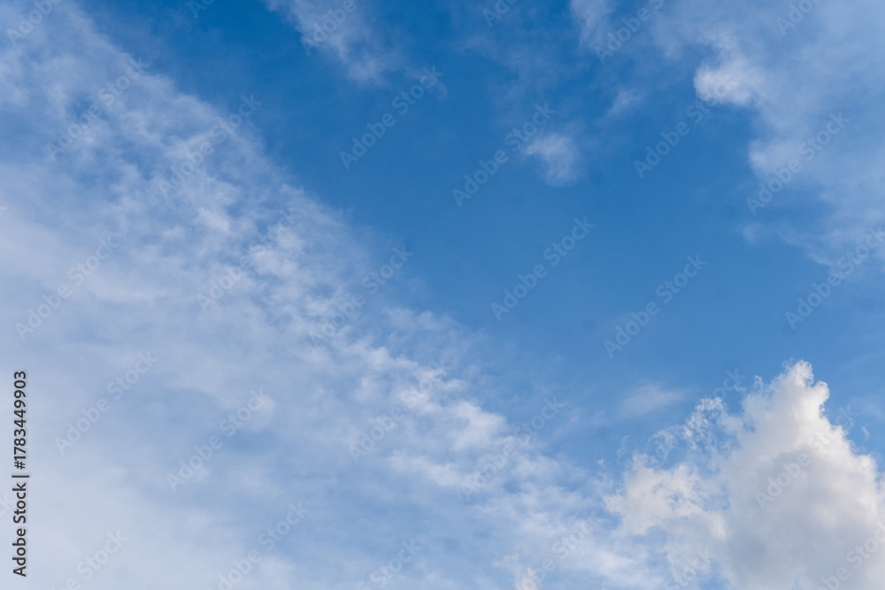 Fototapeta premium A clear blue sky background with layers of thin, wispy cirrus and altocumulus clouds. A bright, sunny day scene representing good weather and serenity. 