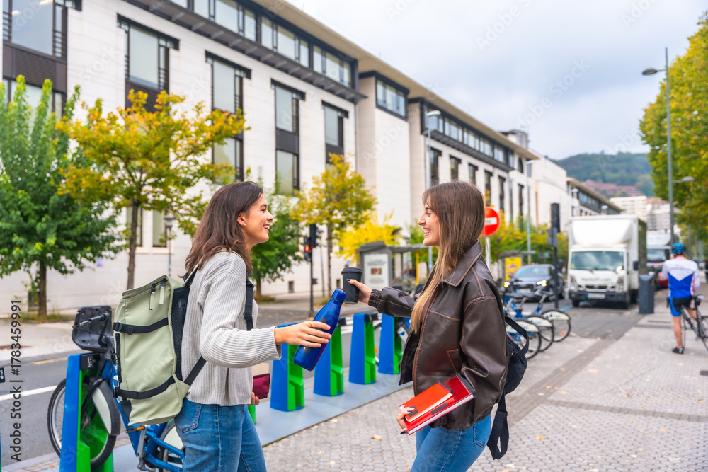 Fototapeta premium Young student friends sharing a flask and talking outdoors
