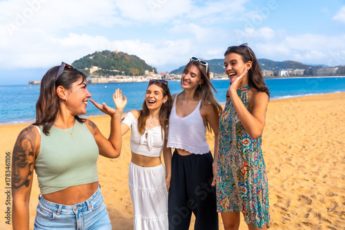 Happy young women enjoying summer vacation laughing on beach in san sebastian