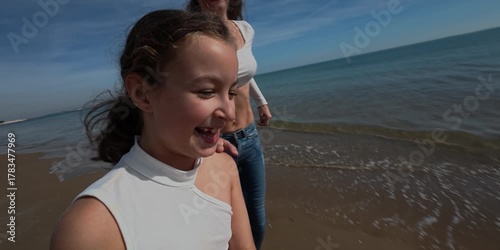 A mother and her daughter are running and enjoying on the beach