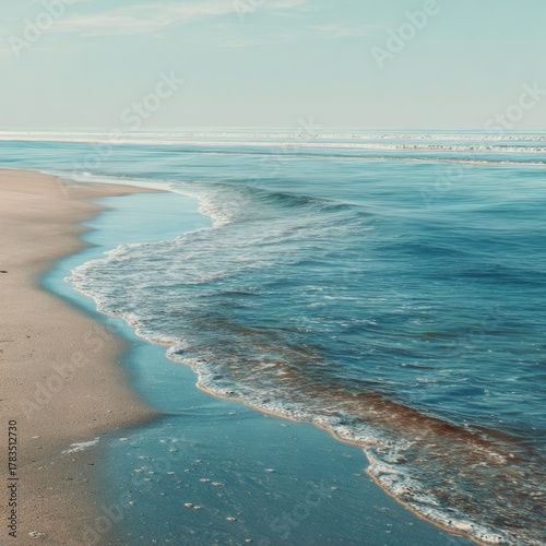 Serene Beachfront Scene with Gentle Waves and Soft Sand Under a Clear Sky, Inviting View for Relaxation and Leisure, Perfect for Travel and Nature Themes
