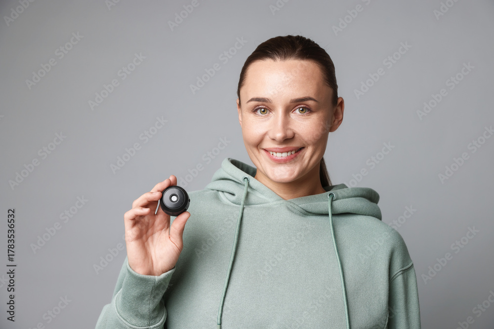 Fototapeta premium Young woman with hidden spy camera on light grey background