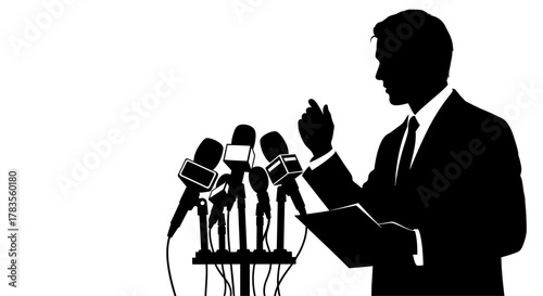 Silhouette of a person in a suit speaking into multiple microphones at a podium