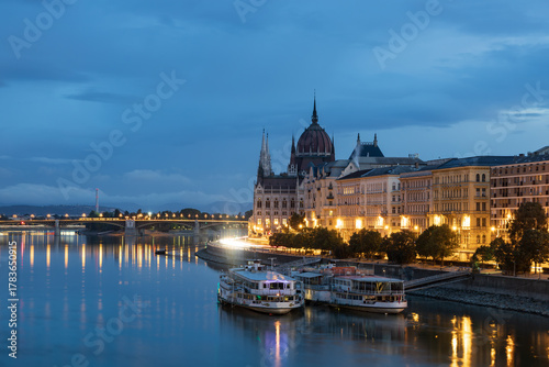 Photography Cruise boats moored in the Danube river next to the 1905 Gothic Renaissance styl