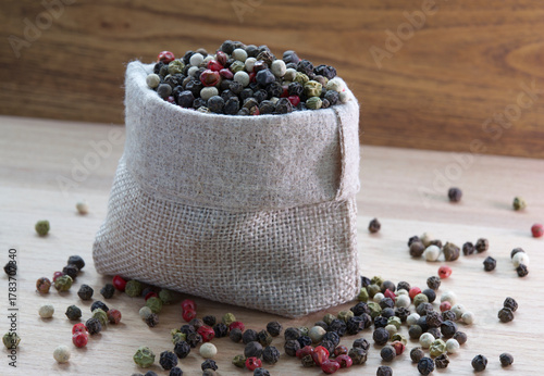 Mixture colored peppers in a canvas sack on wooden kitchen table.