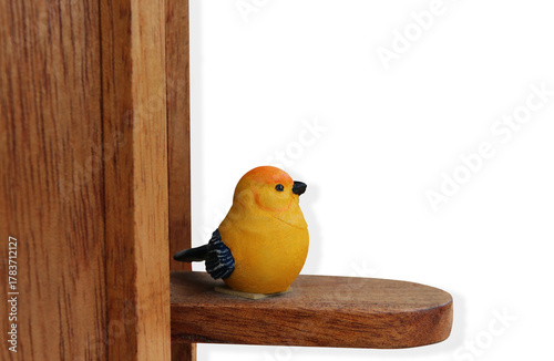 A small yellow bird statue decorated on a wooden pole on isolated background