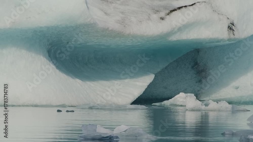 view of a large, ancient iceberg with stunning blue hues floating calmly in the Jökulsárlón glacial lagoon in Iceland