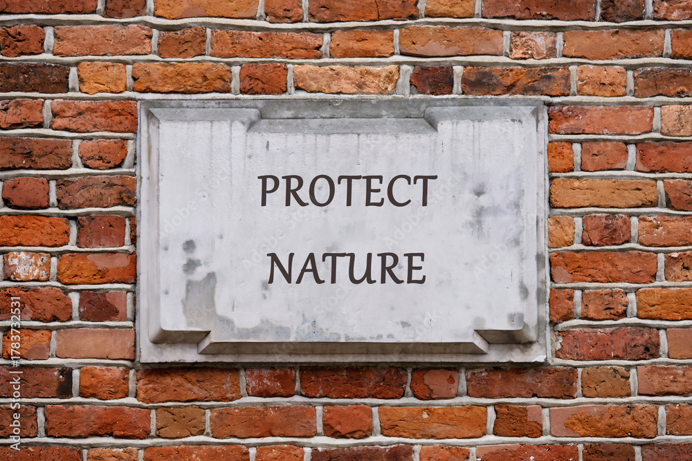 Fototapeta premium A weathered sign on a brick wall boldly declares the message to protect nature. This reminder highlights our responsibility to care for the earth and its resources