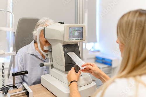 Εκτύπωση καμβά Female ophthalmologist observing paper printout from slit lamp while examining s
