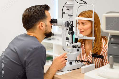 Foto Male ophthalmologist conducting slit lamp eye exam on female patient during chec