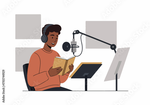 Smiling male narrator recording an audiobook or podcast in a studio, reading from a book into a professional microphone setup.